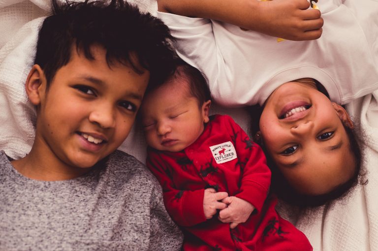 overhead shot of broth and sister with newborn brother in the middle