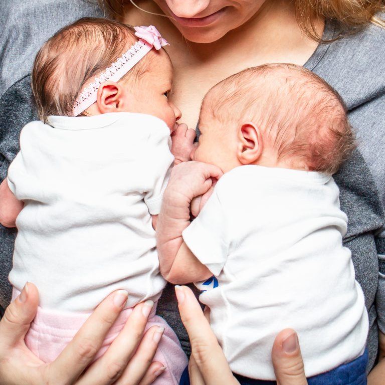 newborn twins rest on their mother's chest during a lifestyle newborn session