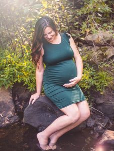 a pregnant woman sits with her hand under her belly