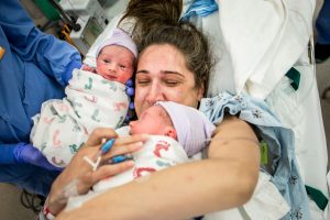 new mother holds twins right after csection birth